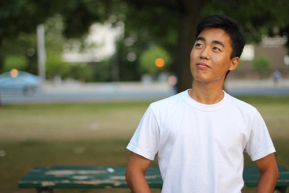 Sam, North Korean man in white t-shirt, looks out in the distance.